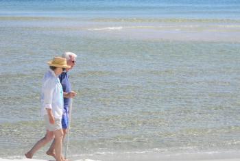 年长的夫妇橙色海滩散步