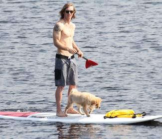 男子和狗在桨板奥兰治海滩AL