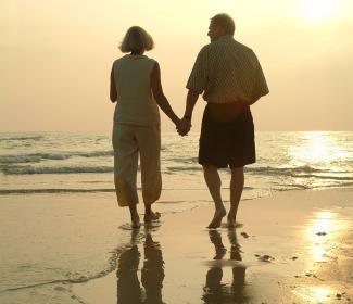 老夫妇手牵着手走在海滩上