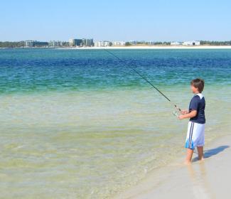 男孩在橙色海滩冲浪钓鱼