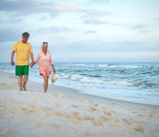 年长的夫妇走在阿拉巴马州的海滩