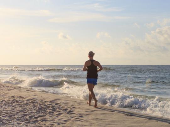 一名女子在阿拉巴马州的白色沙滩上跑步