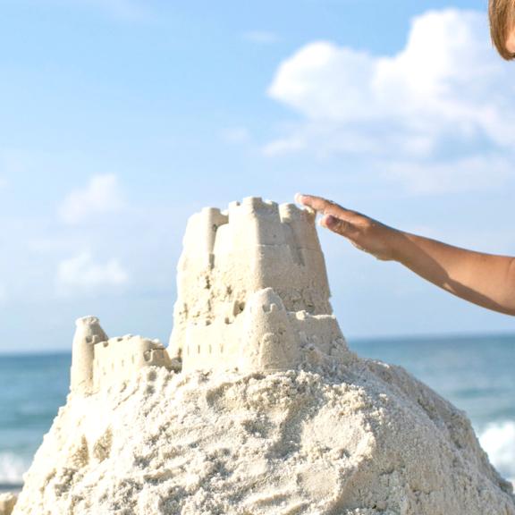 男孩在阿拉巴马州的海滩上建造沙堡