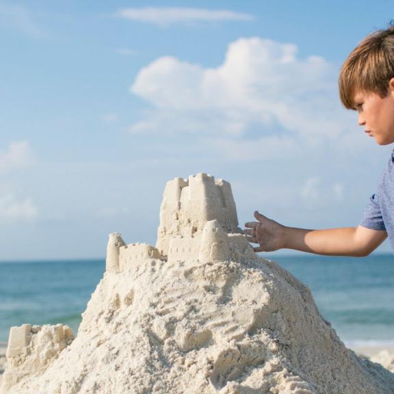 小男孩在奥兰治海滩建造沙堡